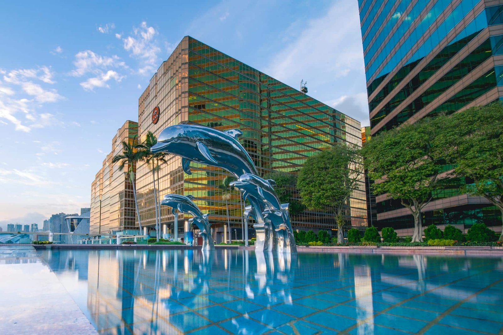 photo/three-blue-dolphins-statue-front-of-water-near-building.